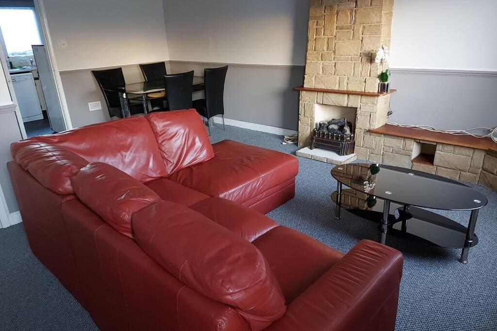 考文垂Wonderland Guest House的客厅配有红色真皮沙发和壁炉
