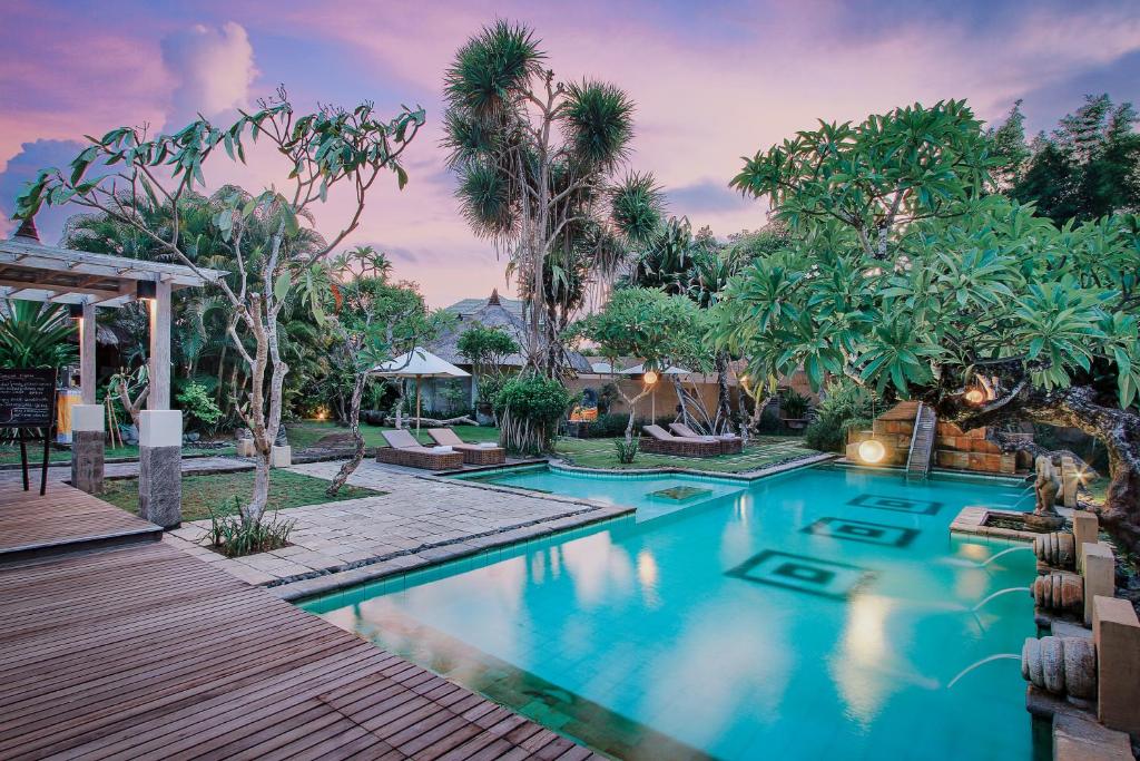 沙努尔Visakha Sanur的棕榈树度假村内的游泳池