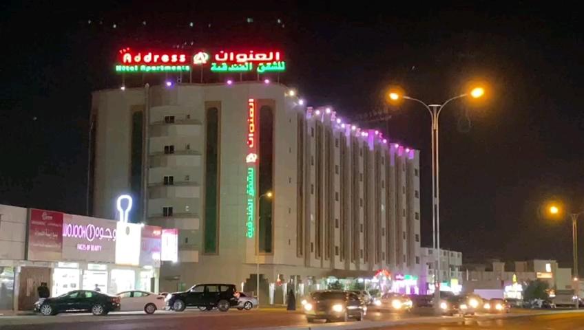 Aş Şa‘arahAddress hotel Apartments العنوان للشقق الفندقية的一座大建筑,晚上有 ⁇ 虹灯标志