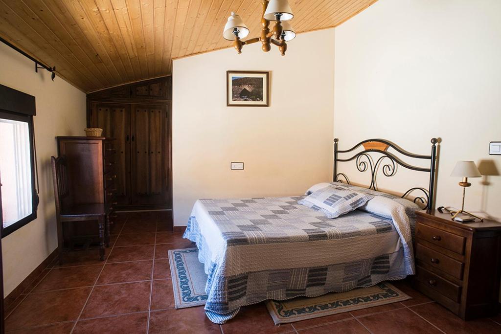 OvejuelaCasa Rural El Chorritero的一间卧室设有一张床和木制天花板
