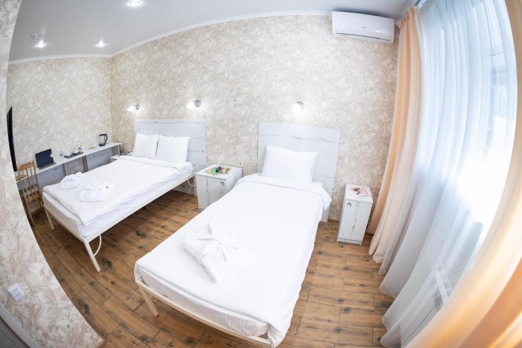 奔萨Авангард Новый Отель的客房设有两张床和盥洗盆。