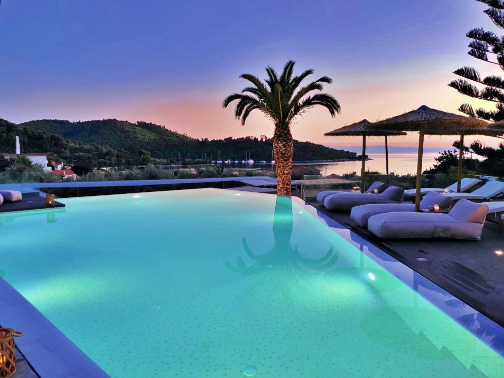 帕诺尔莫斯斯科派洛斯Panormos Beach Hotel Skopelos的一个带躺椅的游泳池,并种植了棕榈树