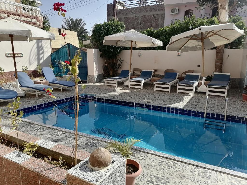 卢克索Luxor palace Apartments的一个带躺椅和遮阳伞的游泳池