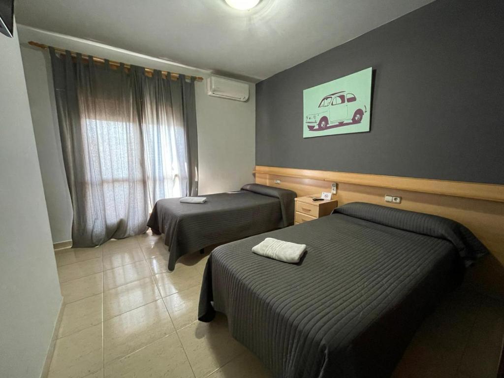 特拉萨Hostal del Carmen的酒店客房设有两张床和窗户。