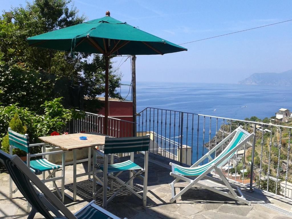 马纳罗拉ARIA DI MARE, Manarola - Camere con vista mare!的一张桌子和椅子,配有绿色遮阳伞和海洋