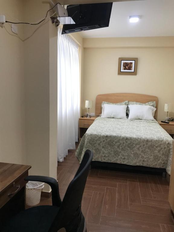 利马Apartamentos Las Americas的一间卧室配有一张床、一张书桌和一台电视
