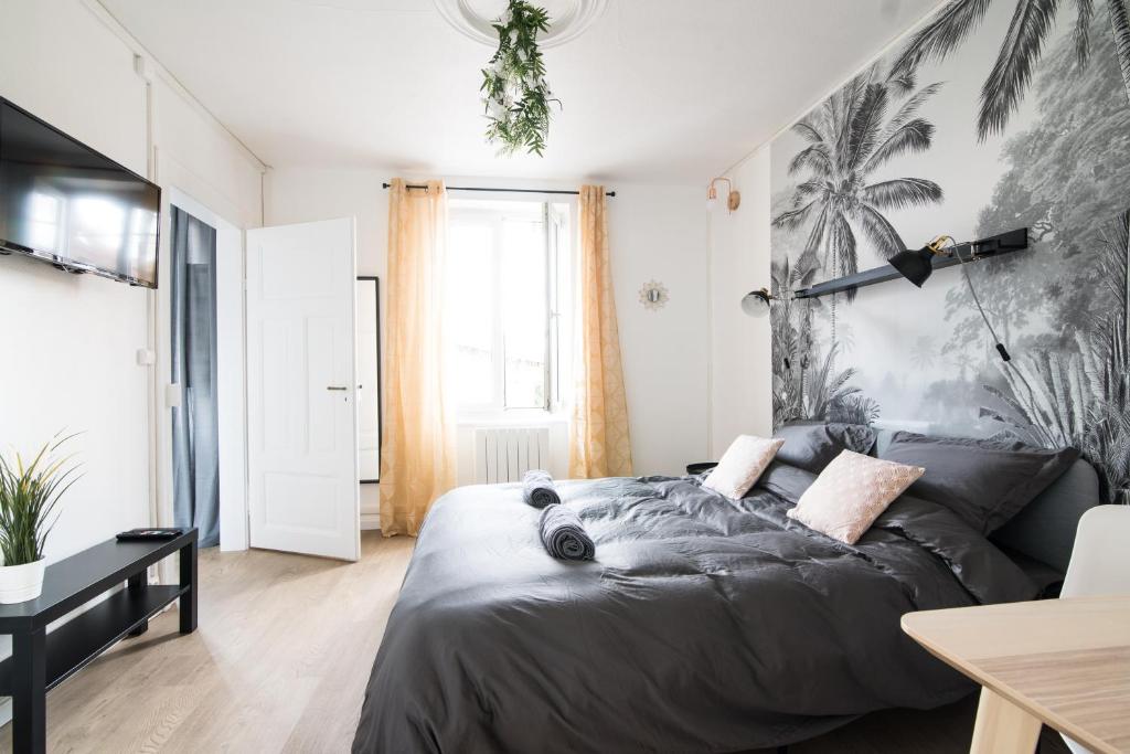萨维尔纳Auguste, La Romaine et My César - Location Saverne的一间卧室配有一张带棕榈壁画的黑色床。