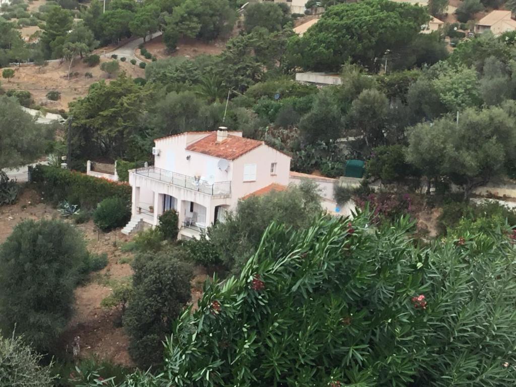 CasaglioneVilla indépendante climatisée Tiuccia Bord de mer的一座白色的房屋,位于一座小山上,有树木和灌木丛