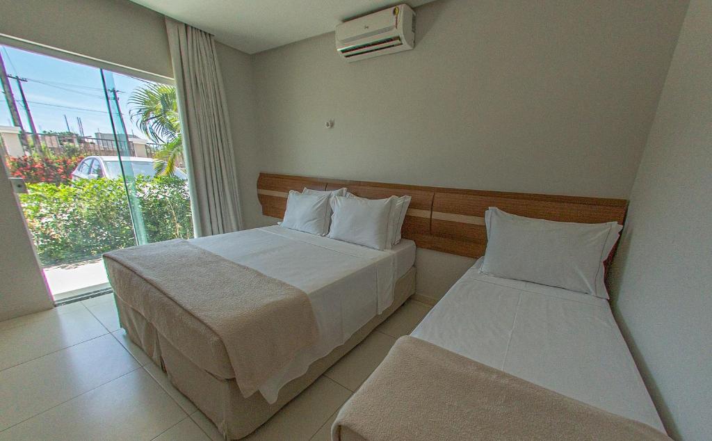 塞古罗港Orquídeas Praia Hotel的酒店客房设有两张床和窗户。
