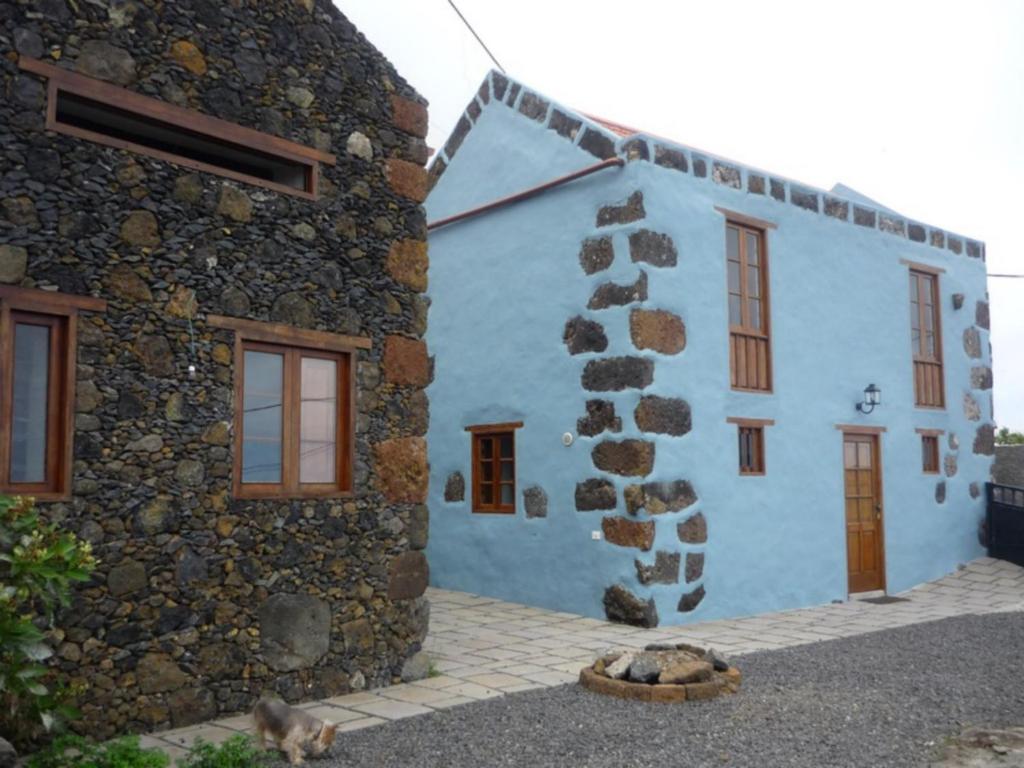 GuarazocaCasa Rural El Tenique的蓝色的建筑,前面坐着一只猫