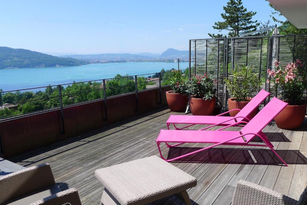 维里尔·杜·拉克Le Clos Du Lac - location de chambres的阳台配有粉红色的椅子,享有水景