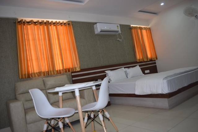班加罗尔hotel fortune suites的卧室配有一张床、一张桌子和椅子
