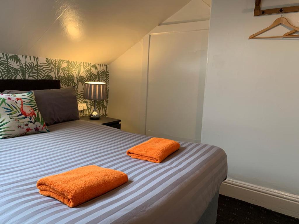 布莱克浦Tropics Beach Hotel的房间里的床上有两个橙色枕头