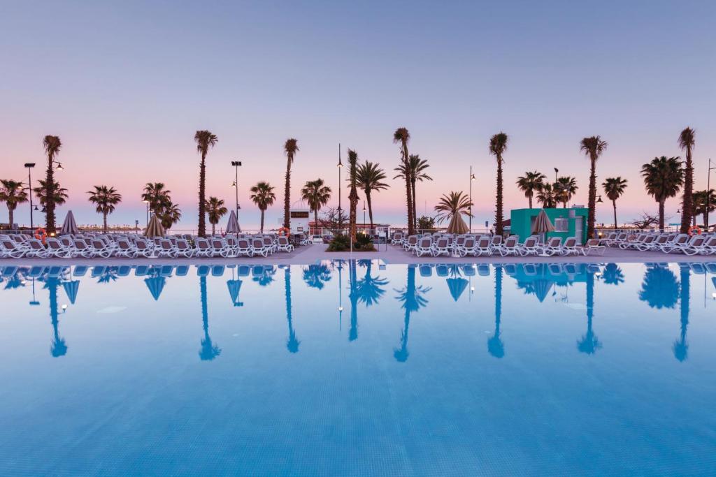 多列毛利诺斯Hotel Riu Costa del Sol - All Inclusive的一个带椅子的游泳池,棕榈树