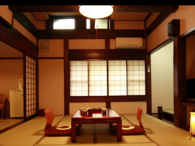 高山村山日式旅馆的客厅配有桌子和两把椅子