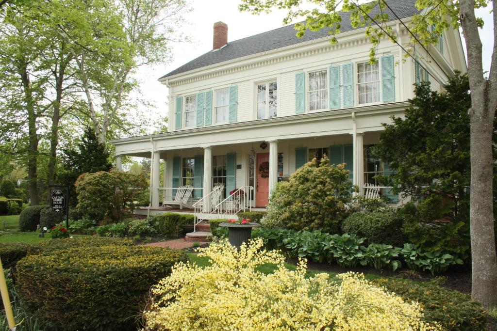 南雅茅斯Captain Farris House的白色的房子,有蓝色的窗户和灌木