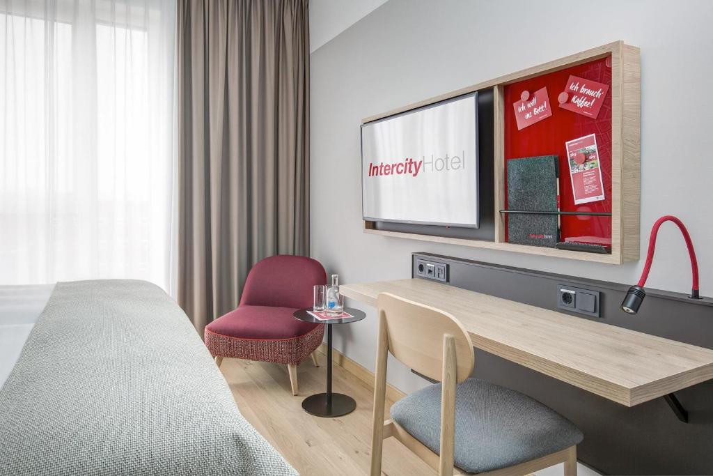 威斯巴登IntercityHotel Wiesbaden的酒店客房设有一张床、一张书桌和一台电视机。