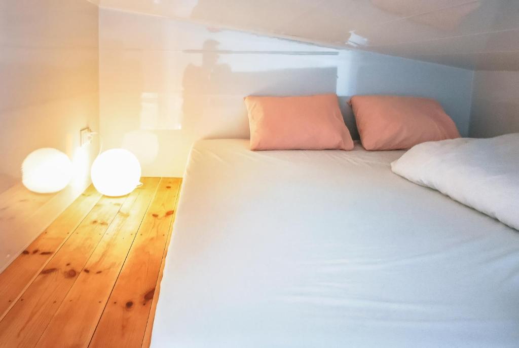 ReguliceLushHills - Tiny House - Modern House On Wheels的卧室配有白色的床和2盏灯,位于地板上