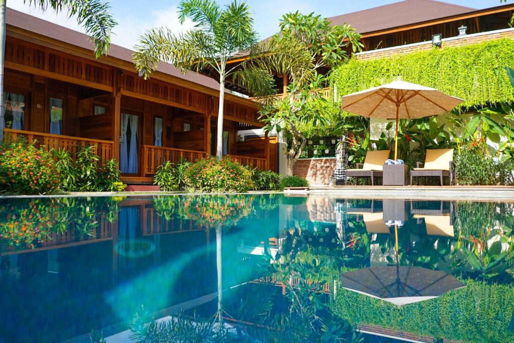 龙目岛库塔La'villaris hotel & resto的一个带遮阳伞和房子的游泳池