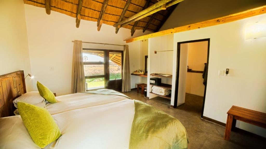 PalmPalmwag Lodge的卧室配有一张带黄色枕头的大型白色床。