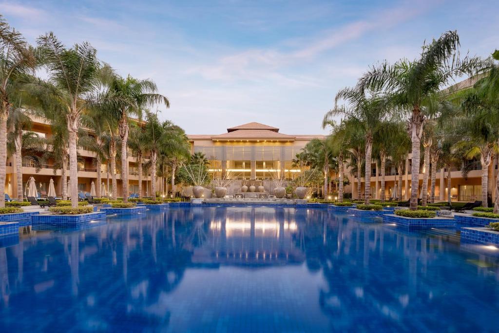 开罗开罗朱斯萨尼湖景酒店的棕榈树建筑前的带游泳池的度假村