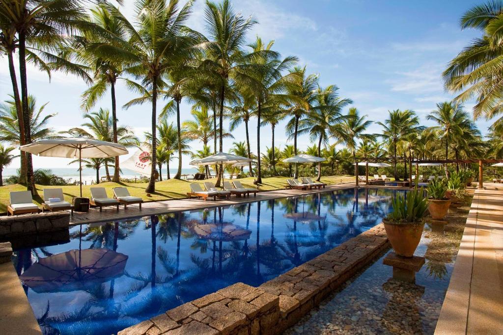 伊塔卡雷特克塞度假酒店的一个带椅子和遮阳伞的游泳池以及棕榈树