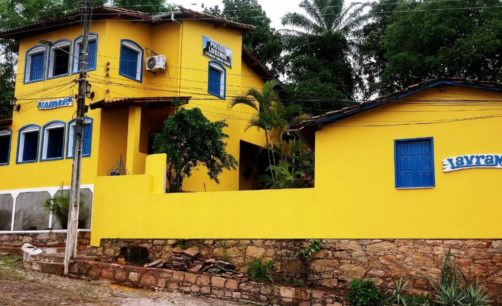 伦索伊斯Pousada Lavramor的黄色的房子,有蓝色的窗户和石墙