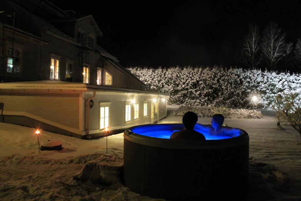 Nedre Vanbo万博赫尔嘉德酒店的两人晚上坐在房子前面的热水浴缸中