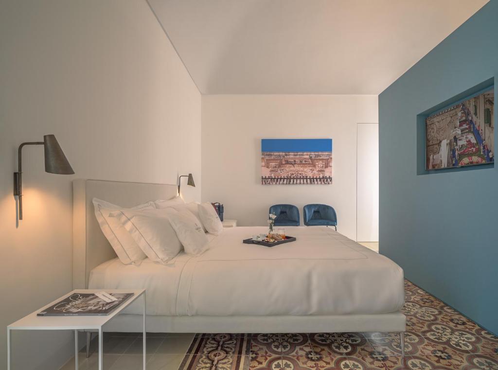 诺托Sikelia Suites的一间卧室配有一张白色大床和两张蓝色椅子