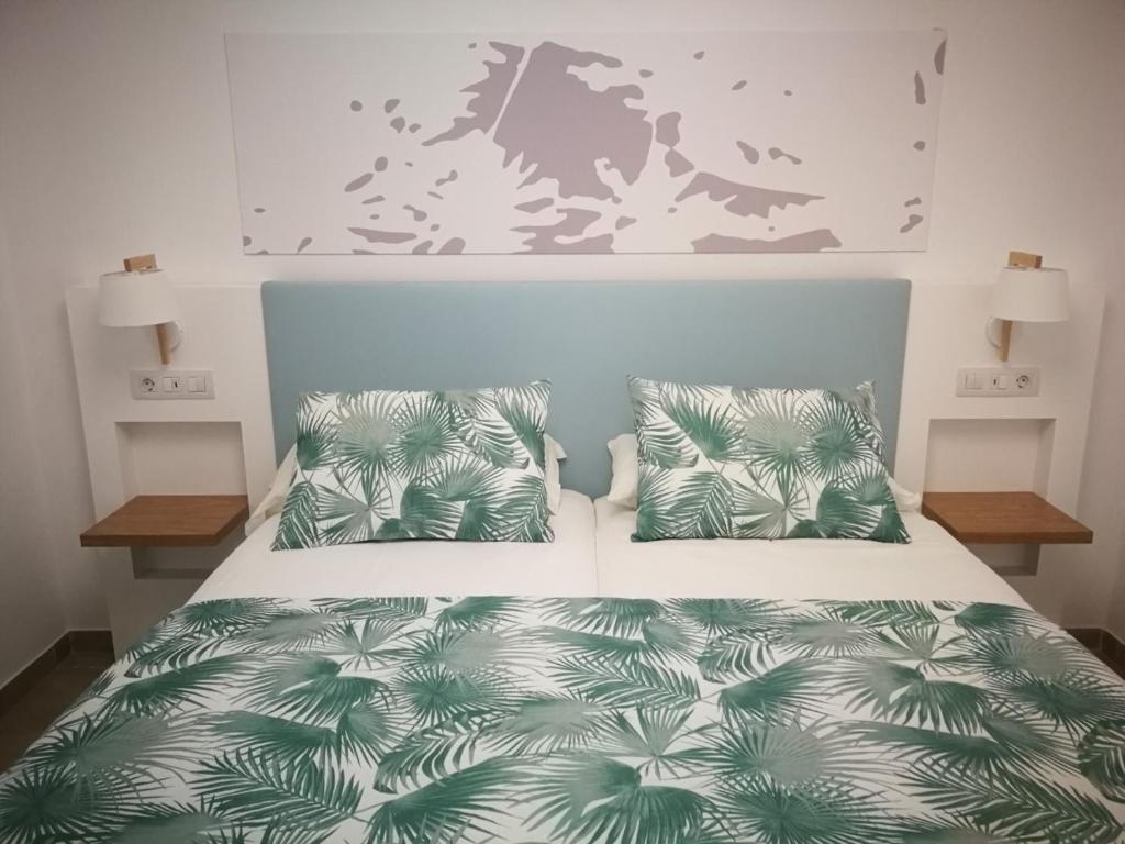 英格兰海滩Apartamentos Corona Playa的一间卧室配有一张带绿色和白色床单及枕头的床。