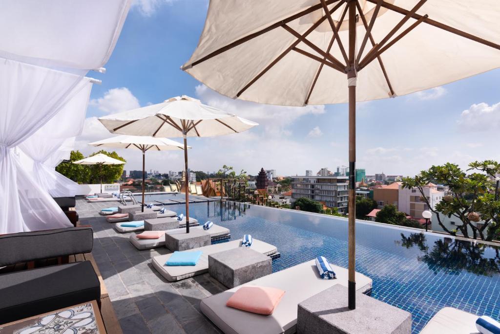 金边PATIO城市度假酒店的一个带遮阳伞和躺椅及桌子的室外游泳池