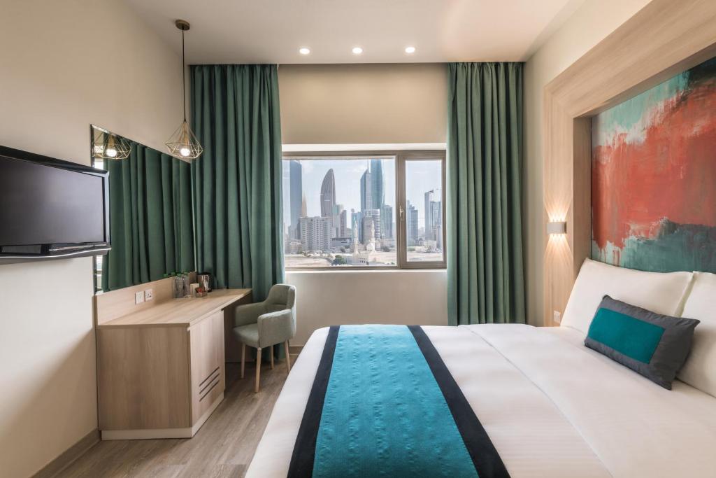 科威特绿洲酒店 的配有一张床、一张书桌和一扇窗户的酒店客房