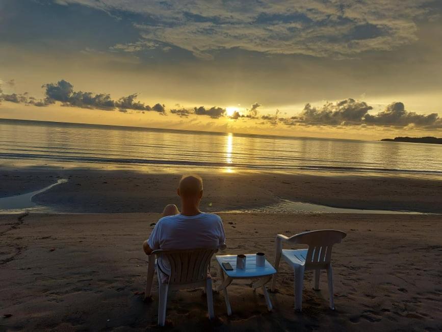巴旺Bella's Beach Resort Apartment 8的坐在海滩上看日落的人