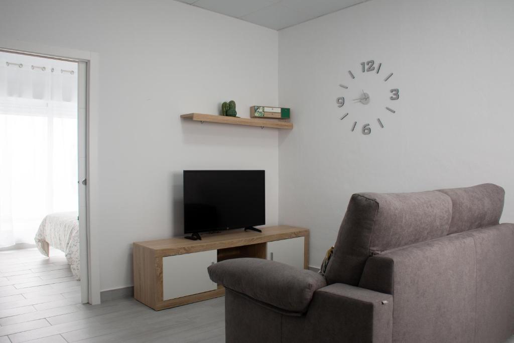 贝赫尔-德拉弗龙特拉Apartamento Calma的客厅配有椅子、电视和时钟