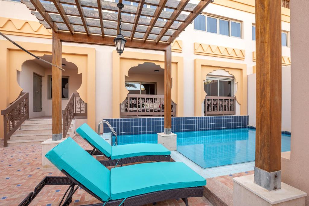 迪拜Exclusive Escapes Private Pool Homes and Villas by GLOBALSTAY Holiday Homes的一座带蓝色家具的游泳池的房子