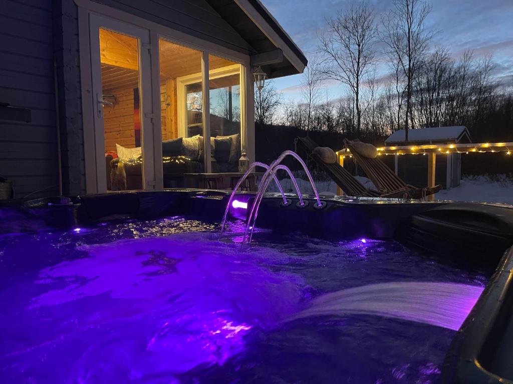 NuorgamAurora mökki porealtaalla Lapissa Tenojoen rannassa的房屋前方的紫色热水浴池