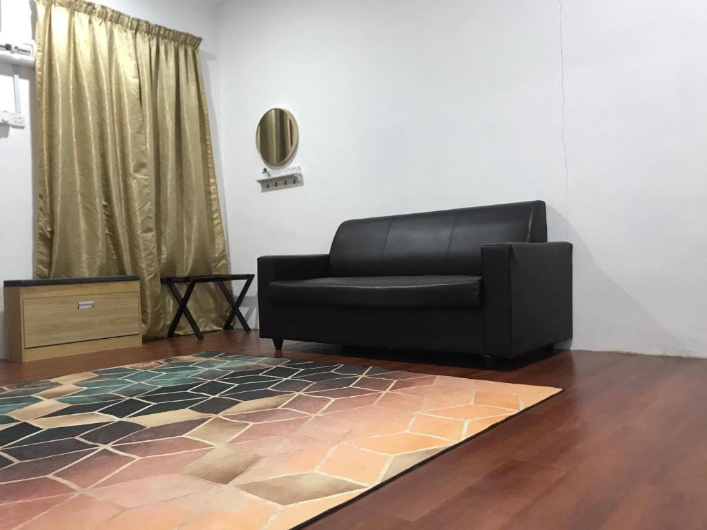 珍南海滩Laman Hanaz - Homestay Auni的客厅里一张黑色沙发,铺着地毯