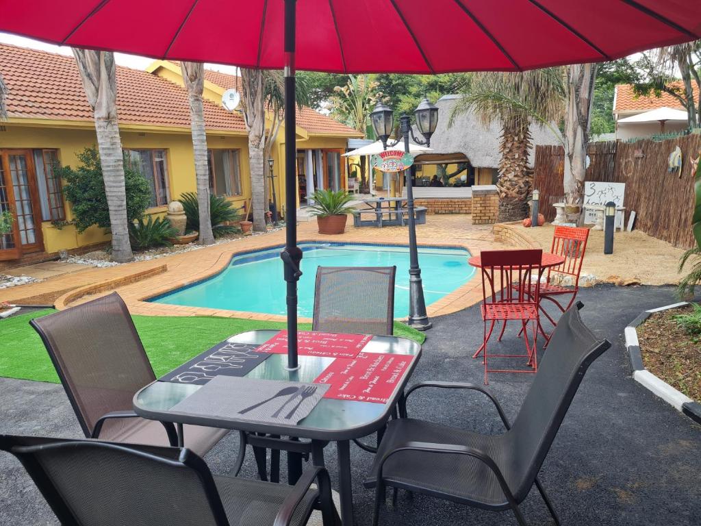 伊登维尔三兄弟住宿加早餐酒店的游泳池旁遮阳伞下的桌椅