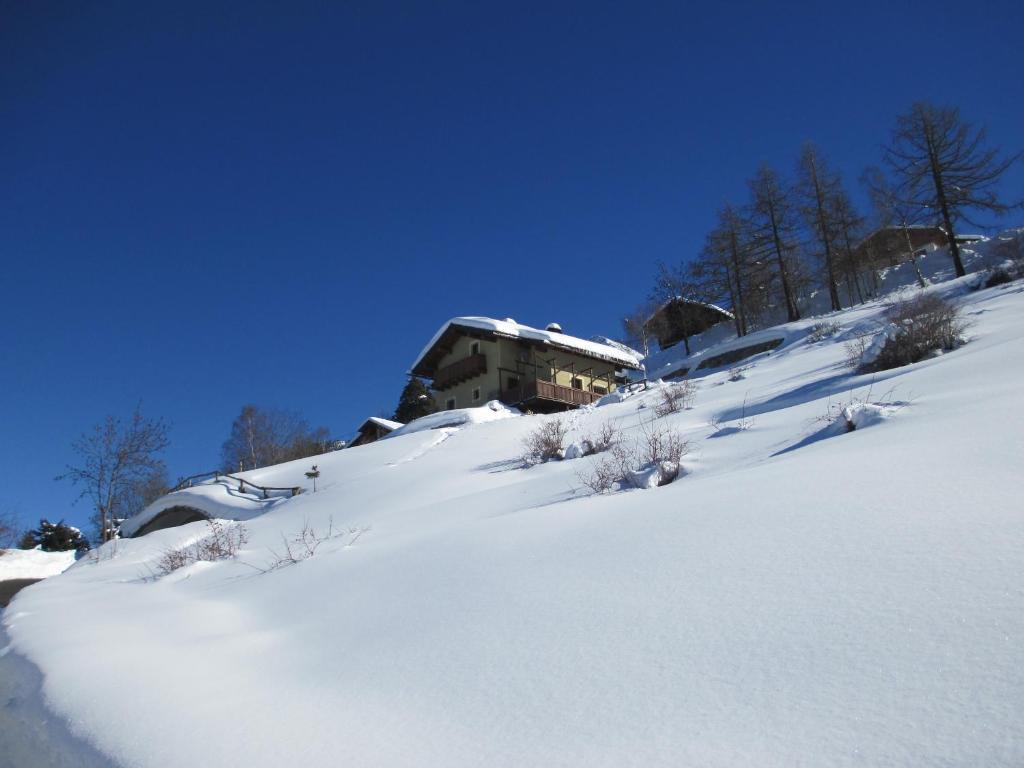 格雷桑Petite Cerise的一座有雪覆盖的山丘,后面有一座建筑