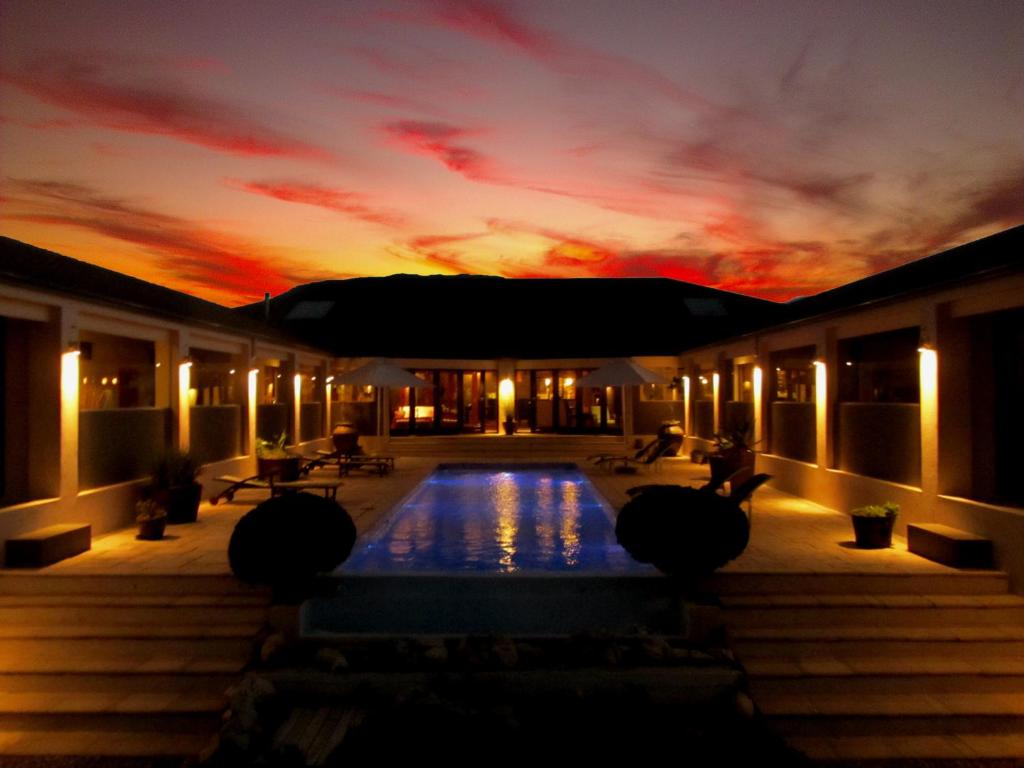 普林格尔贝伊Kapensis Guesthouse (Pty) Ltd的一座房子,设有一座享有日落美景的游泳池