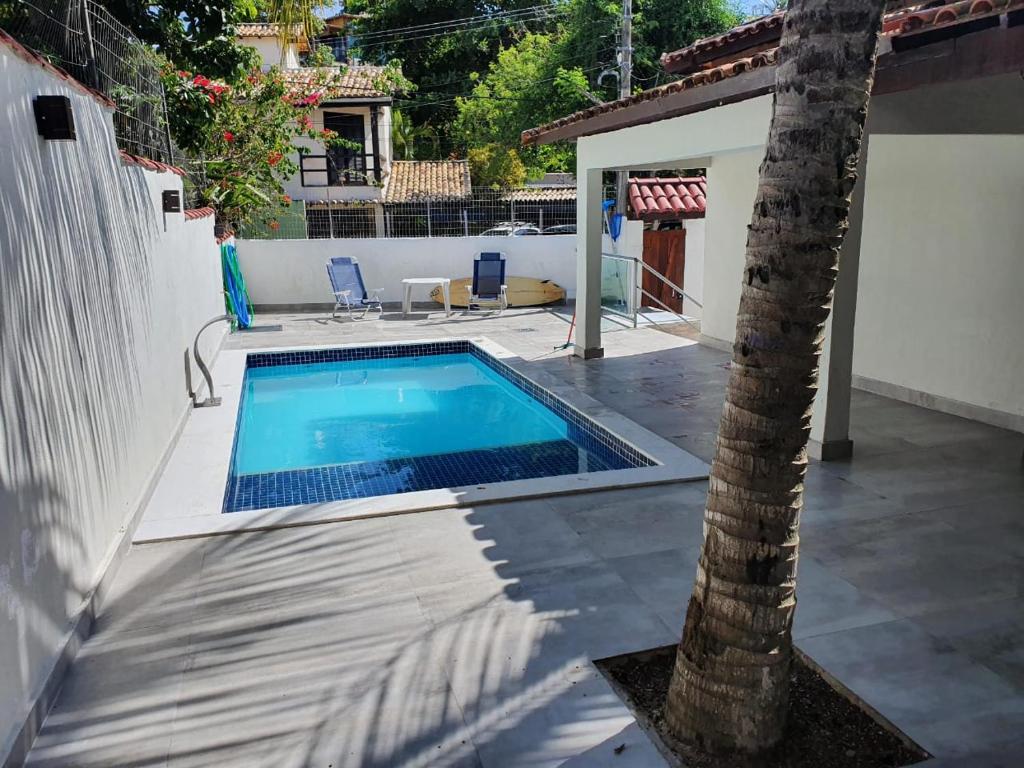 布希奥斯Casa do Tio Eri - Geribá - 100 metros da Praia的庭院中棕榈树的游泳池