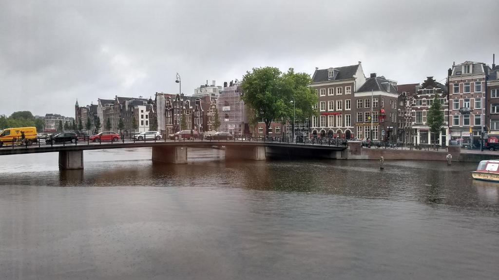 阿姆斯特丹Rembrandt Square Boat的一座建有建筑物的城市里河流上的桥梁