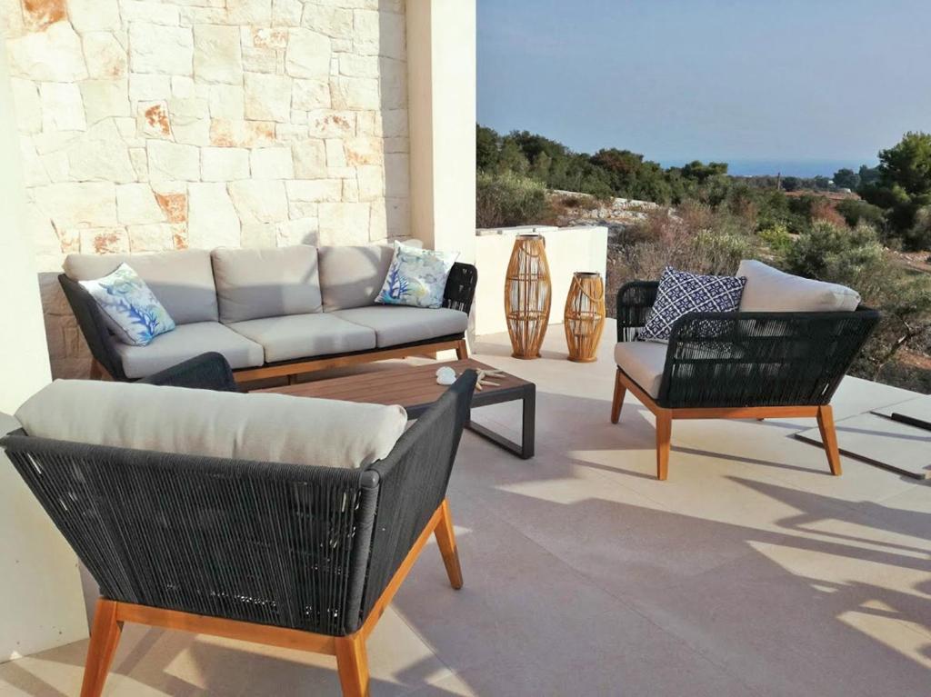 托瑞帕利Villa Briosa Maldive del Salento Pescoluse的天井配有沙发、两把椅子和一张桌子