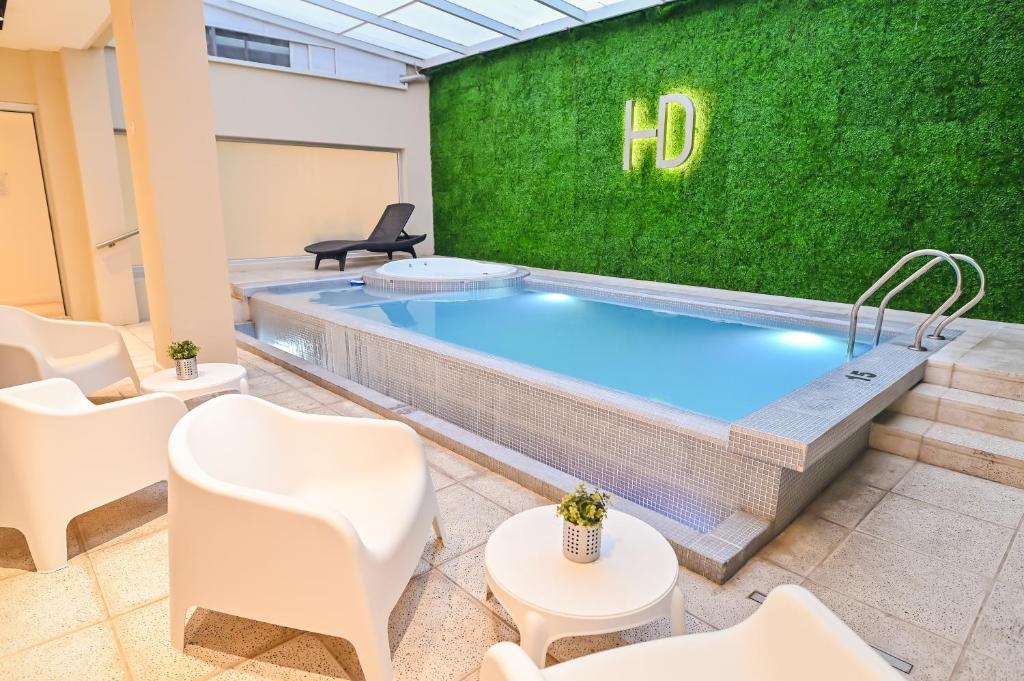 马德普拉塔丹佛马德普拉塔酒店的一个带绿色墙壁和白色椅子的游泳池