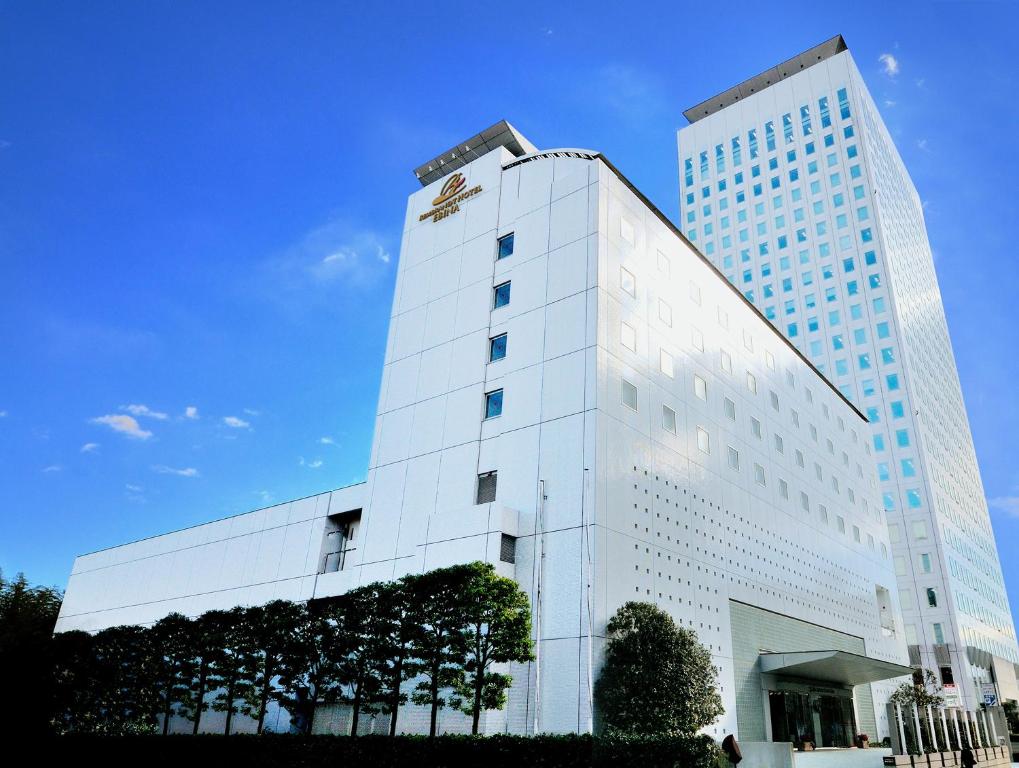 海老名市Rembrandt Hotel Ebina的一座高大的白色建筑,上面有标志