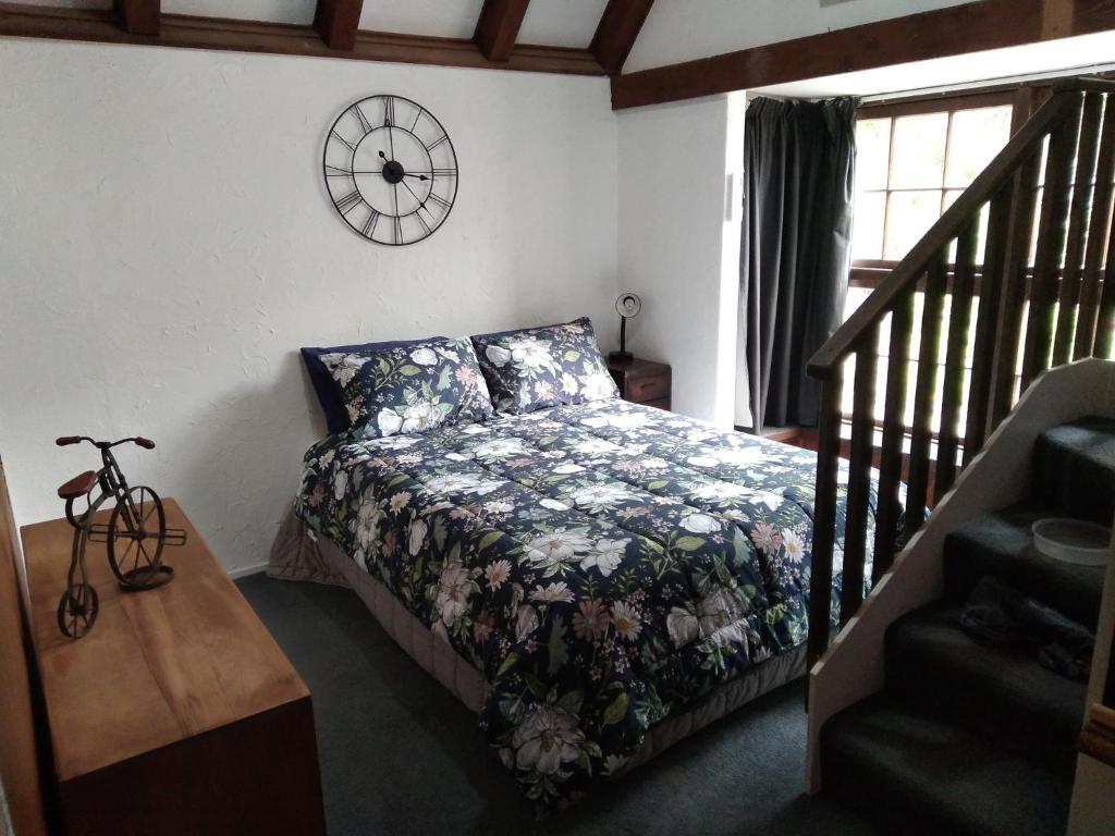 但尼丁Arden Country House - The Chalet Bed and Breakfast的卧室配有一张床,墙上挂着一个钟