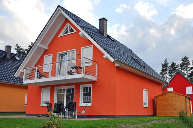 马林费尔德Ferienhaus Müritzbrise / OG-Appartement的带阳台和椅子的红色房子