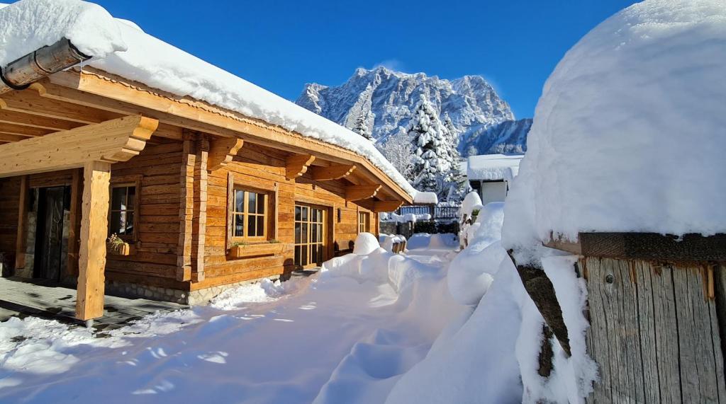 埃尔瓦尔德Chalet Zugspitztraum的小木屋,有雪覆盖,有山背景