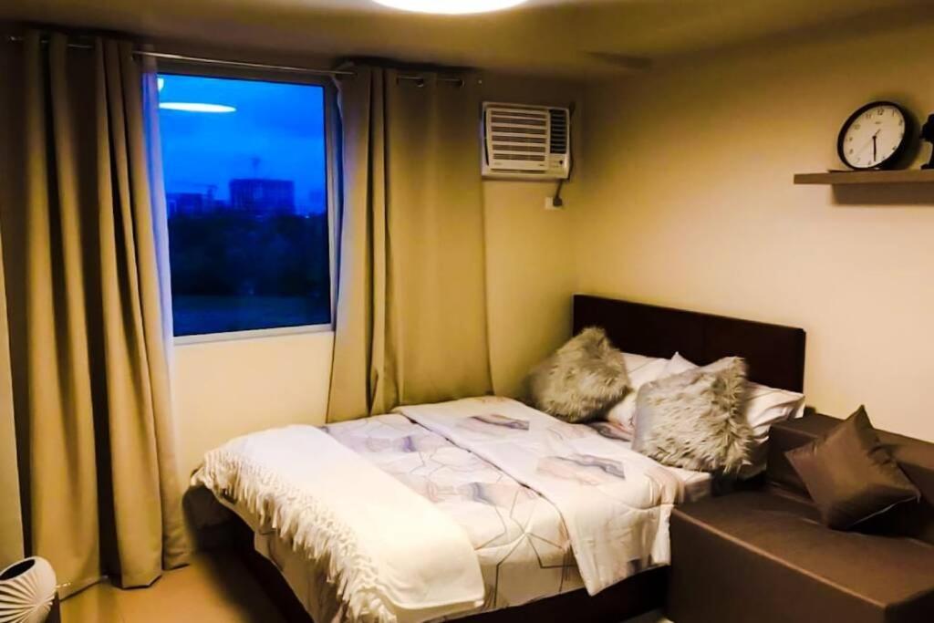 伊洛伊洛Zen Living Condo at Avida Atria Tower 2的一间卧室配有一张床和一个带时钟的窗户