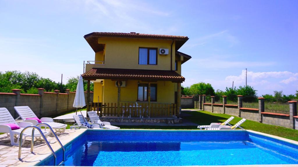 布尔加沃Вила Делфин - Villa Delfin的一座房子,里面设有游泳池、椅子和一座房子